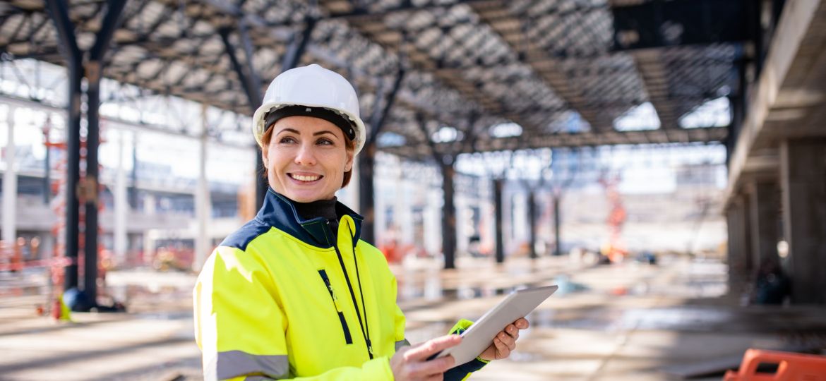 A woman engineer with tablet standing on construction site, working.