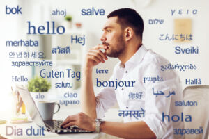 translation, business, and technology concept - male translator or businessman with laptop computer thinking at office over greeting words in different foreign languages. man with laptop over words in foreign languages
