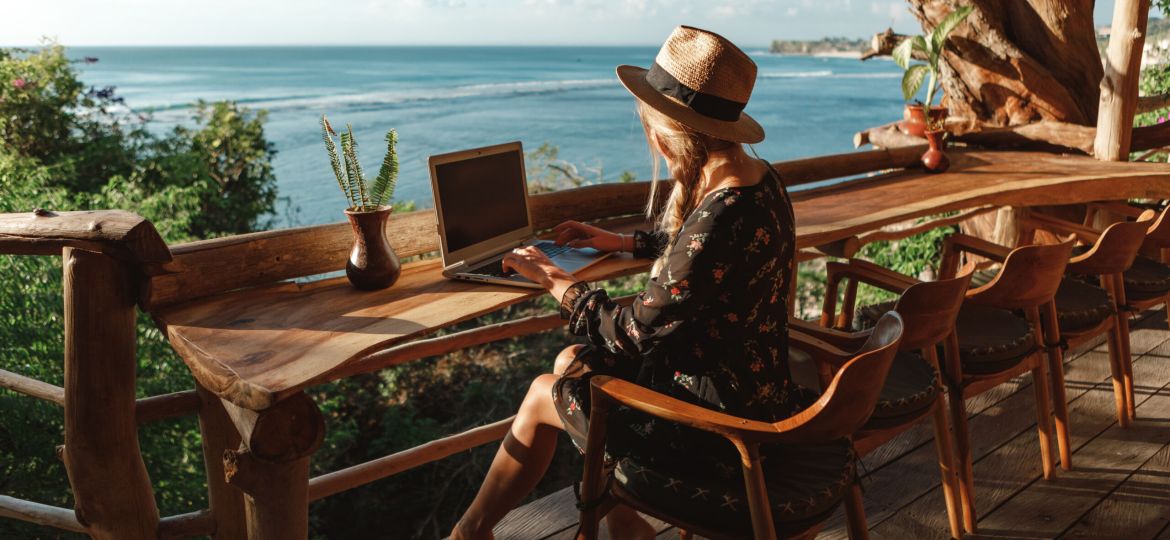 Freelance concept. Pretty young woman using laptop in cafe on tropical beach in outdoor cafe terrace with sea view. Work and travel. Freelance concept. Pretty young woman using laptop in cafe on tr